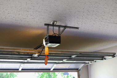 Garage door motor unit mounted on the ceiling above the tracks, viewed from below.