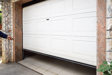 Technician's hand adjusting the ceiling-mounted opener of a newly installed garage door.