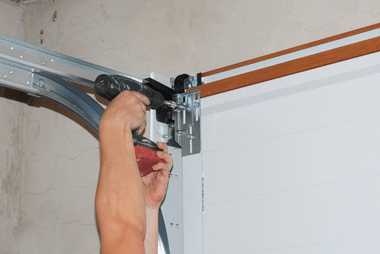 White sectional garage door partly open with a person's arm visible beside it.
