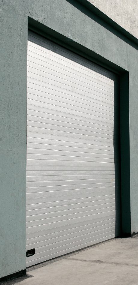 Grey roller-style garage door set into the entrance of a commercial or industrial building.