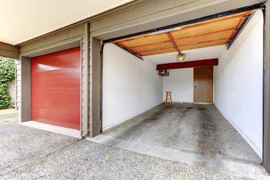 Red roller garage door beside an open garage bay with a clean, empty interior