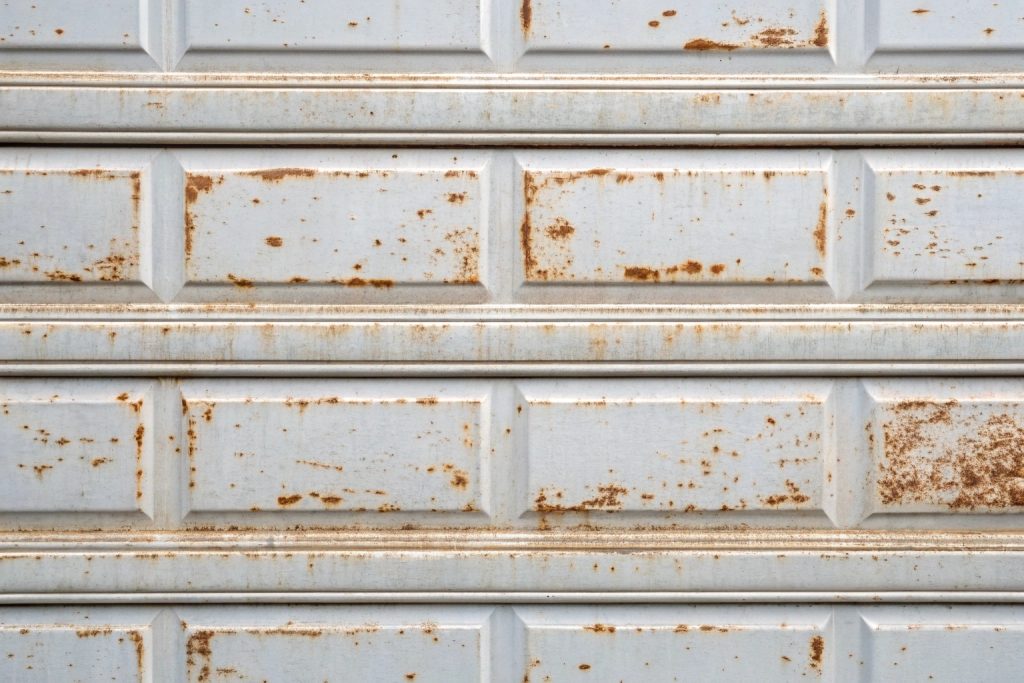 Rusted garage door panel needing replacement in coastal area